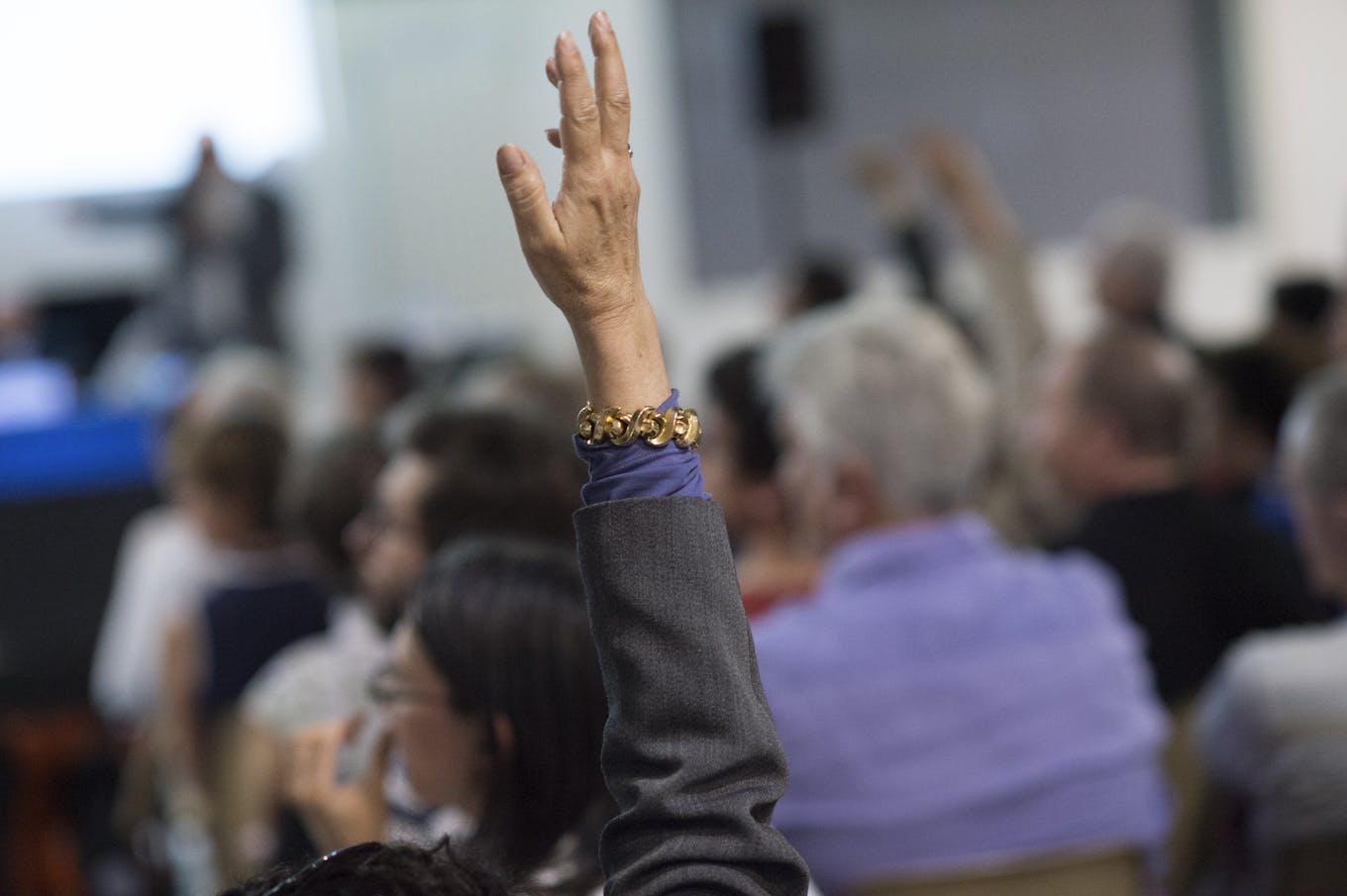 Une participante lève la main en réunion publique