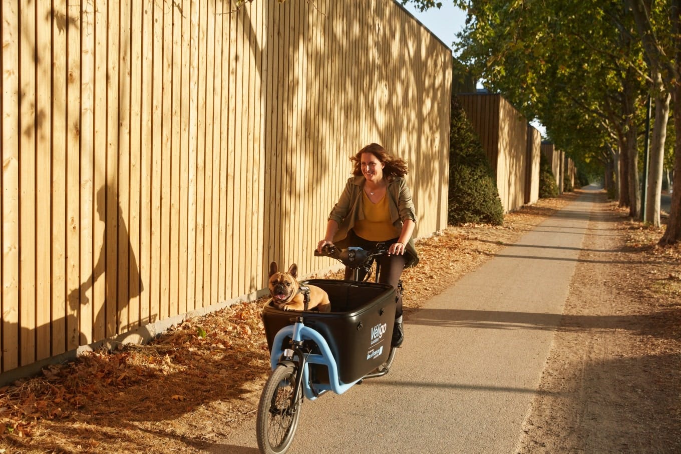 Jeune femme transportant son chien dans un vélo cargo Véligo Location
