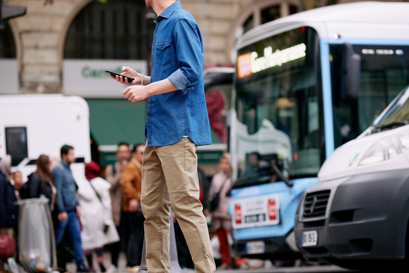 Ein Mann auf der Straße mit Straßenverkehr im Hintergrund und einem Bus
