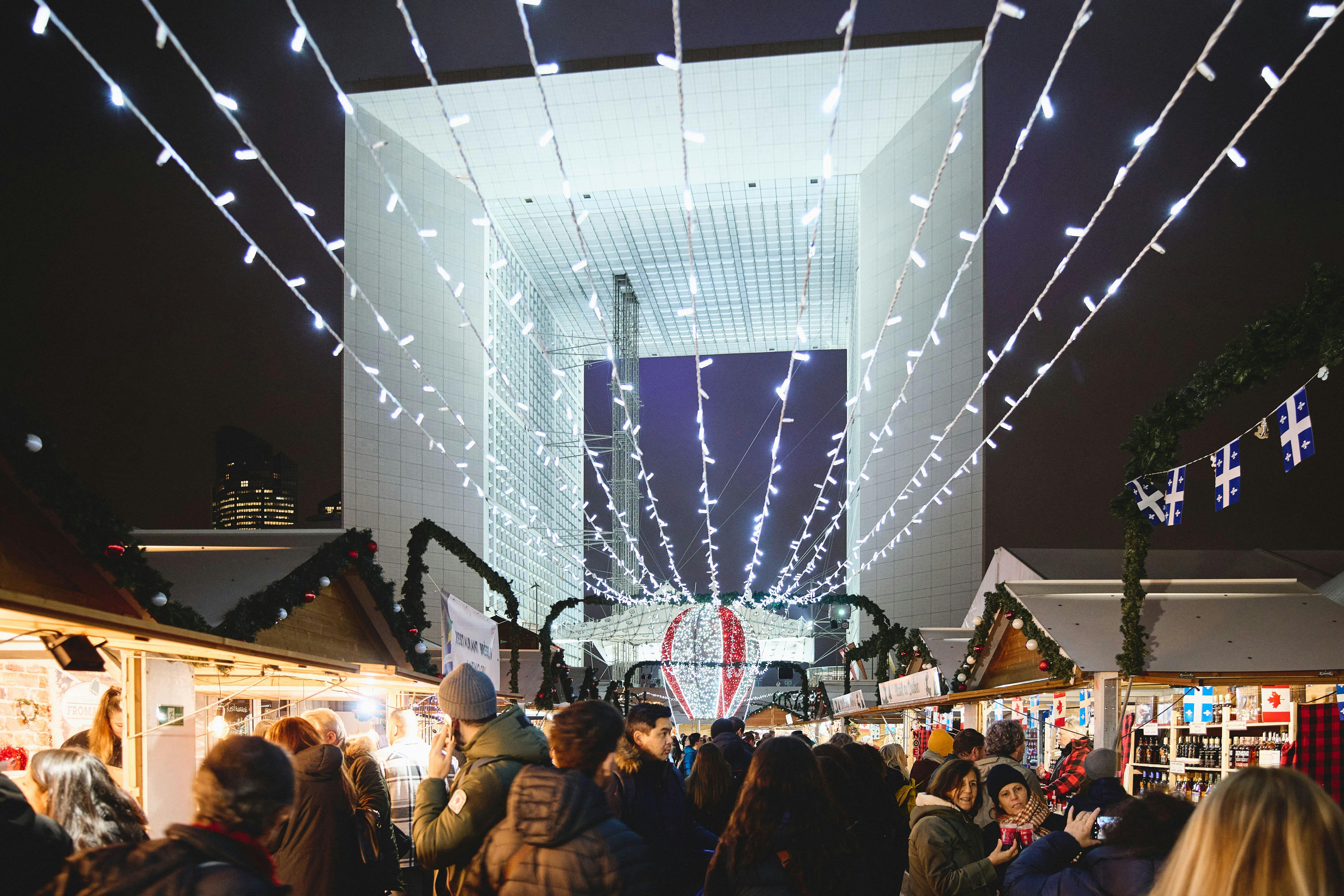O grande Arco de La Défense, ao fundo do iluminado mercado de Natal