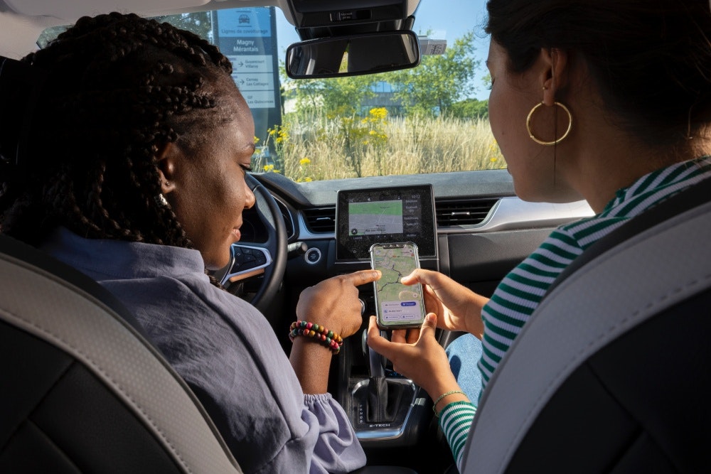 Dos mujeres en un vehículo miran su ruta en un teléfono - Ecov - Gwenn Dubourthoumieu