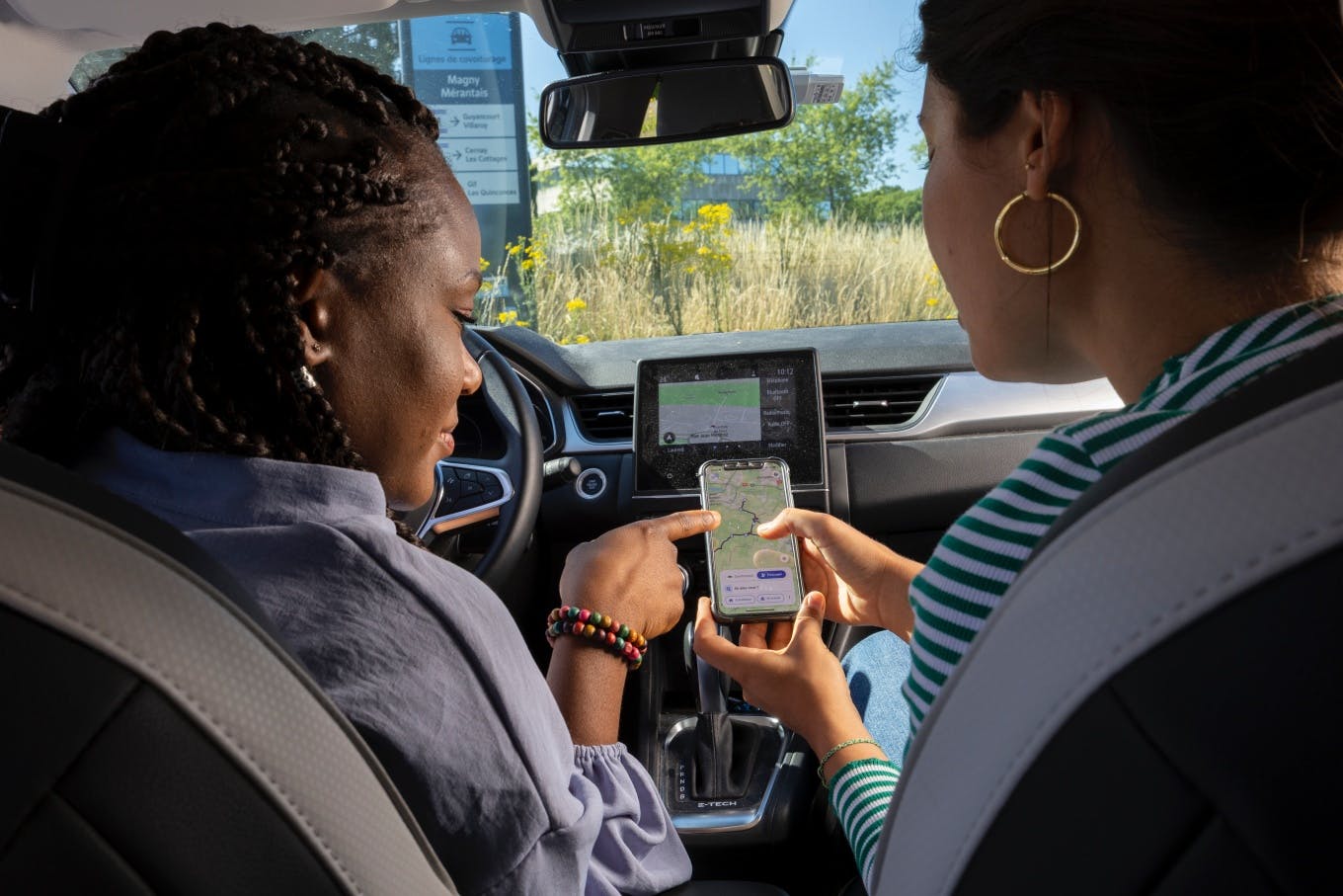 Deux femmes dans un véhicule regarde leur itinéraire sur un téléphone - Ecov - Gwenn Dubourthoumieu
