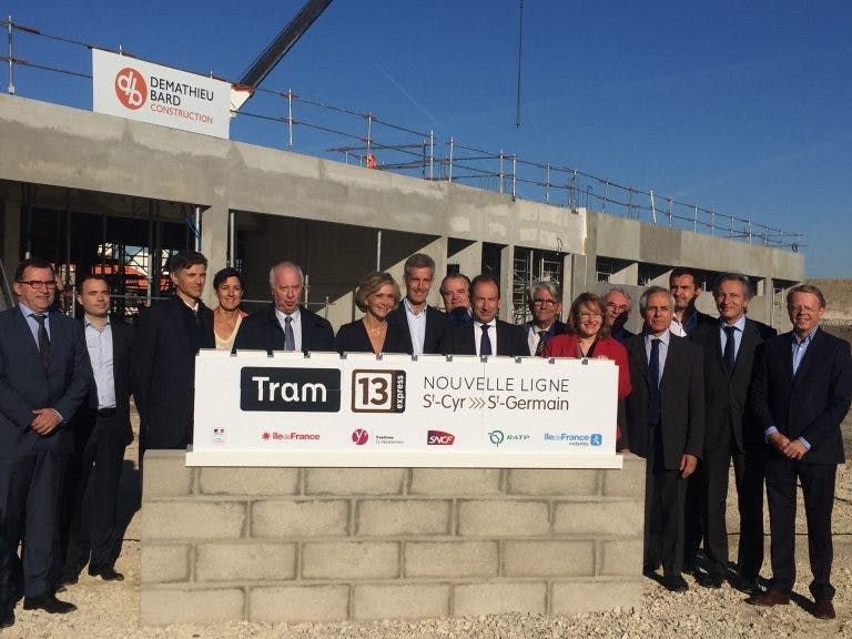 Personnels d'île-de-France mobilités derrière un petit mur et une plaque pour le lancement des travaux du Tram 13 express